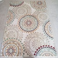 Full view of the rectangular mandala patterned area rug placed on floor showing detailed circular medallion motifs in beige cream base with accent colors.