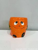 Front view of orange ceramic planter showing smiling face design