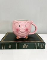 Front view of the pink ceramic pig mug showing the pig's face, ears, and feet detail.