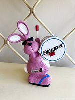 Front view of pink Energizer Bunny holding a branded white drum with a red drumstick, showing logo and overall design.
