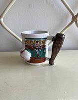 Side view of the vintage ceramic baseball mug showing player illustration and bat-shaped handle.