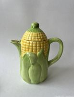 Front view of the ceramic corn teapot showing the detailed corn cob design and green husks.