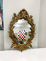 Full front view of vintage oval mirror with gold ornate frame showing overall condition and design details.
