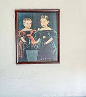 Full view of framed vintage artwork featuring two children in period clothing.