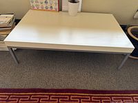 Top view of the coffee table showing white formica surface and straight metal legs
