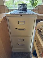 Front view of 2-drawer beige metal file cabinet with handles and label holders on each drawer.