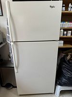 Front view of the white Whirlpool top-mount refrigerator showing the model logo and door handles