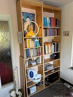 Tall, rectangular wood shelf unit standing upright against a wall. Multiple sections and shelves with no items included as seller confirms items will be removed before pickup.