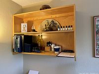 Front view of three-tier wooden shelf unit mounted on wall with various items on shelves for size reference.