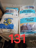 Four pillow cushion forms in original packaging shown on a surface. Two different sizes and brand labels visible.