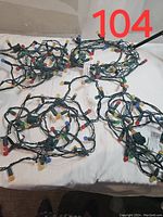 Four coiled strings of small colored bulbs on green wiring, arranged on a white surface.