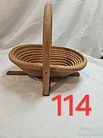 Front side of handcrafted wooden bowl with handle, showing bowl expanded and ribs to collapse bowl.