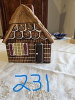 Front view of ceramic cookie jar designed as a gingerbread house with detailed hand-painted windows, door, and roof decorations including cookie accents.