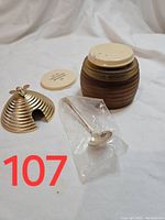 Brown ribbed Avon bath gel container with cream lid, small silver ladle in plastic, gold decorative bee piece shown separately