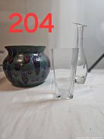 Photo showing the pottery planter and two clear glass vases from front view on white surface with lot number 204