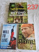 Three Les Stroud survival books arranged on a surface showing all front covers including Beyond Survivorman, Will To Live, and Survive.