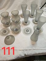 Top view of six tall frosted dessert glasses with removable bases, and six individual saucers laid flat, along with six frosted dessert bowls turned upside down.