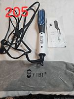 YIBI branded electric beard straightener brush with power cord, instruction manual, and grey YIBI carrying pouch laid out on white surface.