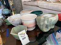 Overview of all pots on a table including the elephant planter, round gradient pot, white wavy edged pot, and hexagonal green pot.
