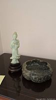 Front view showing both jade figurine and stone bowl on display surface