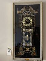 Full view of framed clock parts wall art depicting a stylized clock design with a central clock face surrounded by various clock gears and metal pieces on a black background.
