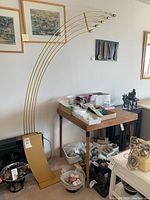 Full view of mid-century modern arch floor lamp with curved brass-tone arms and weighted base