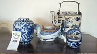 Group photo of four blue painted porcelain items including tea pots and a vase