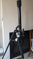 Full view of the telescope mounted on its tripod against a wall.