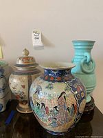 Image showing three varnishes: The large oriental vase with crackling, the turquoise urn with rings, and the cream colored vase with floral accents and lid.