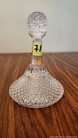 Image of full view of the lead crystal decanter showing the diamond cut pattern and stopper on wooden surface.