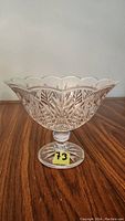 Front view of the lead crystal pedestal bowl on wooden surface, showing scalloped rim and detailed leaf pattern design.
