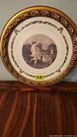 Full view of the round framed print showing the classical art scene and ornate wood frame.
