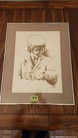 Full view of framed signed print showing a woman holding a child, sketch style in sepia tones with label 47.