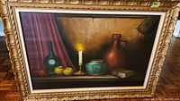 Framed still life oil painting by Van Dorp showing candle, fruits, pottery, and a book on a shelf.