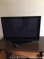 Front view of the Panasonic 42-inch plasma TV and the remote control on the wooden table in front of it.