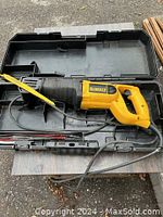 DeWalt yellow and black cordless reciprocating saw with attached cord inside black carrying case, along with some blades.