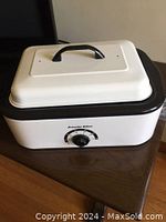 White and black electric roaster with lid and front dial control.
