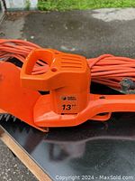Close-up photo showing the handle and main body of the electric hedge trimmer with Black & Decker brand and 13" marked on the unit.