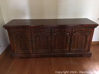 Front view of the wooden hutch cabinet showing four paneled doors and decorative trim on top.