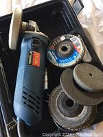Photo showing Ryobi 4-1/2 inch angle grinder inside black carrying case with six assorted discs.