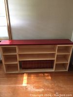 Wooden shelf with red top and multiple open compartments, containing encyclopedia set.