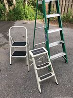 Photo showing all three step ladders together on pavement with grass and fence background