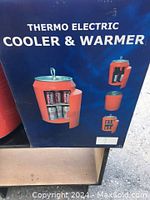 Front box showing the product name Thermo Electric Cooler and Warmer with image of the red can-shaped device holding cans inside.