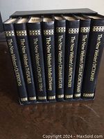 Photo of 9 black hardcover Webster's books with gold embossed titles on spine, titles visible and set neatly in a stand.