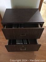 Front view showing top and both drawers open revealing metal file hangers inside.