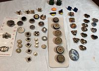 Full lot display showing various button covers and cufflinks arranged on a table with a white cloth.