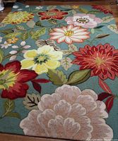 Full view of area rug showing multicolor floral design on turquoise background