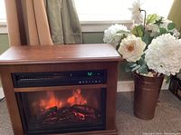 Electric fireplace with simulated glowing logs and flame effect, digital control panel showing temperature 72°F and control icons.