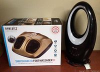 Box and massager device of Homedics Shiatsu Air 2.0 foot massager, new in box, gold and black color.
