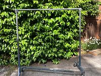Heavy duty rolling clothing rack full frame against greenery background